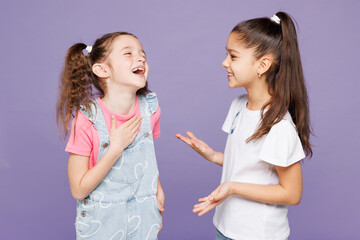 Little smiling cheerful cool two friends kids children girls 9-10 years old wear casual clothes together talking with each other laugh tell joke isolated on plain purple background. Lifestyle concept.