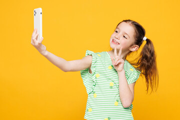 Little kid child girl 8-9 years old wear green t-shirt do selfie shot on mobile cell phone post...