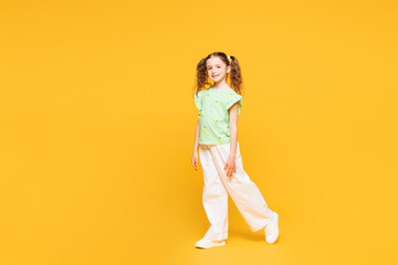 Full body side view little smiling cute kid child girl 8-9 years old she wears green t-shirt...