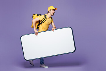 Full body young delivery guy employee man in yellow cap t-shirt uniform workwear thermal bag work...