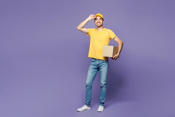 Full body young happy delivery guy employee man wear yellow cap t-shirt uniform workwear work as...