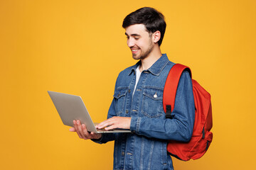 Young smiling smart boy IT student he wear jeans casual clothes backpack bag hold work on laptop pc...