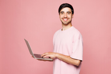 Side view young Caucasian IT man he wear t-shirt casual clothes hold use work on laptop pc computer...