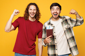 Traveler winner two friends men in red casual clothes hold passport ticket isolated on plain yellow...