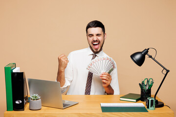 Young winner employee business man wear white shirt tie sit work at office desk with pc laptop hold...