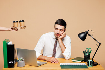 Young sleepy tired exhausted employee business man wear white shirt tie sit work at office desk...
