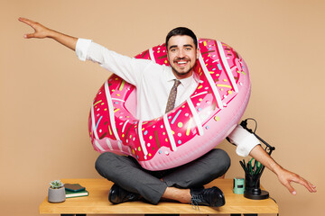Full body young employee business man wear white shirt tie donut rubber ring sit work at office...