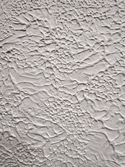 Close-up of textured white painted wall with rough stucco, plaster wall texture. Bright background, wallpaper, backdrop, design element. Exterior finish imitating rough concrete.
