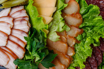 Assorted sliced smoked meats and cheese served on fresh lettuce leaves. Includes smoked pork belly, chicken fillet, salami, hard cheese, pickles, and parsley. Traditional appetizer platter.
