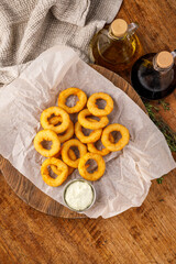 Crispy onion rings with dipping sauce on parchment paper