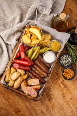 Assorted sausages and pickles with sauces on a metal tray