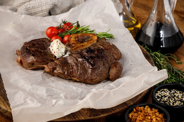 Beef steak with herb butter rosemary and cherry tomatoes on parchment paper