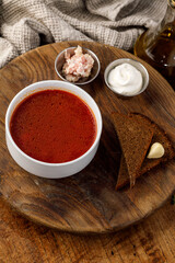 Classic borscht with rye bread lard and sour cream on rustic wood background