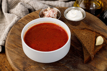 Traditional borscht soup with sour cream rye bread and pork fat on wooden board