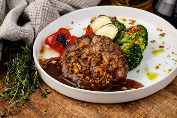 Grilled meat with vegetables and sauce on white plate