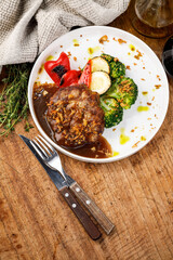 Roast meat with grilled vegetables and brown sauce on ceramic plate