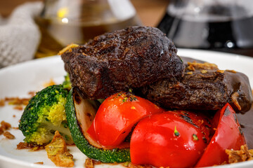 Closeup of roasted beef with zucchini and bell peppers on plate