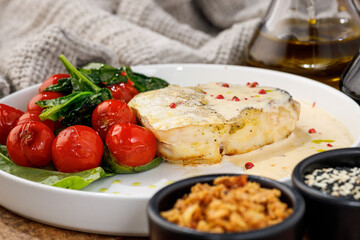 White fish fillet with creamy sauce spinach and cherry tomatoes