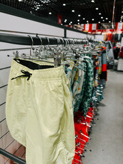 Colorful swim shorts on display in a vibrant retail store during a sunny afternoon
