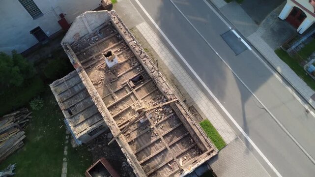 Dismantling of an old wooden roof structure after a calamity. Visible damaged beams and rafters are being carefully removed, showing the process of restoration and rebuilding  