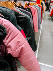 Colorful jackets displayed on racks in a retail store during a busy shopping day