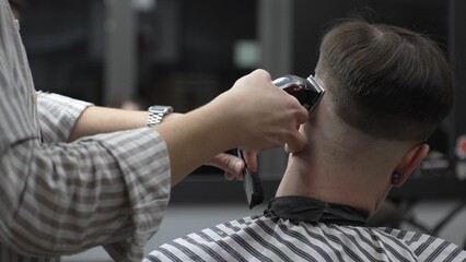 Professional barber cutting client's hair with electric clipper, working precisely in contemporary...