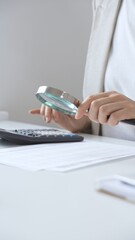 Financial professional analyzing company reports with magnifying glass, checking detailed metrics...