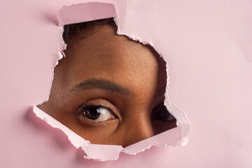 Curious model peeking through torn pink paper