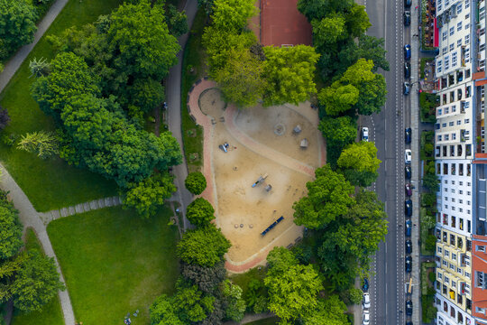 Aerial view of a vibrant playground nestled amongst lush greenery and adjacent to colorful buildings, Friedrichshain-Kreuzberg, Berlin, Volkspark Friedrichshain, Germany.