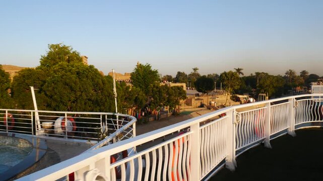 The famous temple in the village named "Kom Ombo", Egypt, on the banks of the river nile. Balustrade of the sundeck of a cruise ship in the foreground. 