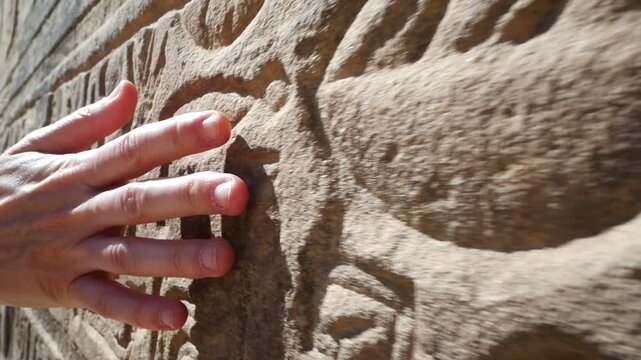 Close up of a woman hand touching a wall with hieroglyphics, at the famous temple of Philae Aswan, Egypt.