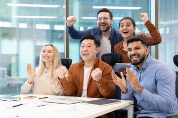 Diverse group celebrating a success together in a modern office setting. They are happy and excited.