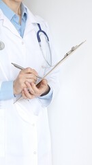 Close up of female doctor wearing stethoscope and white coat over blue blouse is standing and...