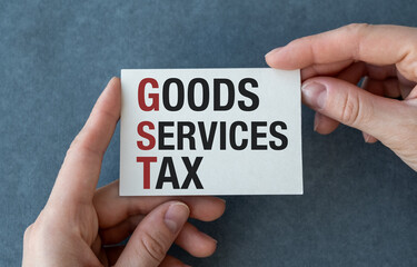 A person is holding a white card that says Goods Services Tax.