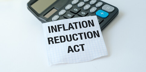 A calculator sits on a table with a piece of paper that says Inflation Reduction Act.