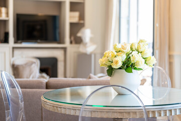 Elegant dining table with white roses in bright living room — stylish and luxurious interior design