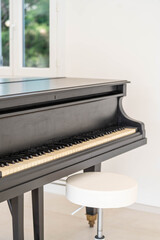 Fototapeta premium Elegant black grand piano in bright minimalist interior with white walls and natural light – refined musical atmosphere