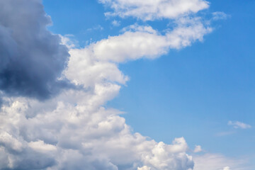 Clouds in the sky shaped like a crescent, white and gray, covering half of the blue sky close-up,...