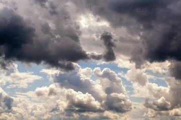 Dark clouds above and light clouds below intersect in the sky, dark and white swirling clouds divide the sky in half close-up, weather change as a sign of bad weather