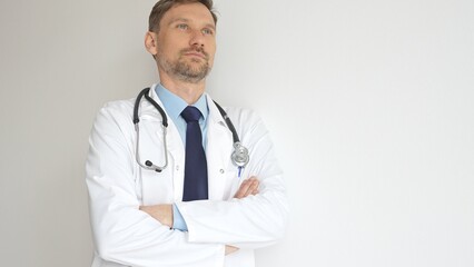 Headshot of a confident doctor man wearing stethoscope and white coat, is standing with crossed...