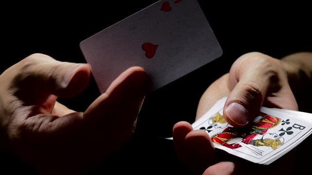A deck of playing cards in the hands of a man on a black background.
The dealer shuffles the cards before the game.
Casino game and dealing cards.
