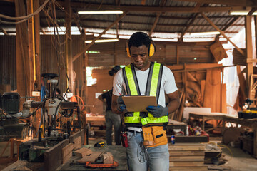 African American Man Working in Timber Factory Performing Quality Inspection on Wooden Planks with...