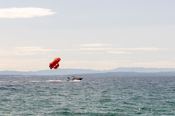 Colorful parachute is soaring above the ocean while a speedboat pulls it, creating an exciting...