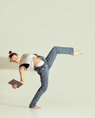 Tech and expression. Graceful performer balancing with leg extended and tablet in hand wearing...