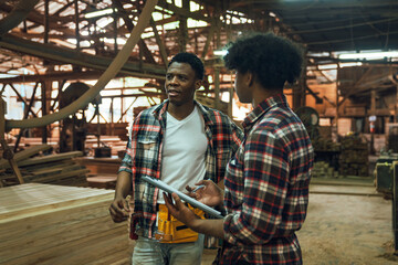 Factory Workers Discussing Work in Timber Sawmill, Two African American Men Collaborating in...