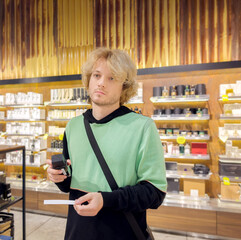 Man buying make up at cosmetics section in store. choosing cosmetics, perfumes, creams and shampoos, Using tester.	