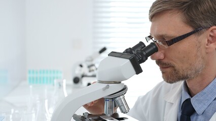 Scientist using a microscope is doing scientific research in a modern laboratory, developing innovative medicine for healthcare. Medicine, healthcare and science concept