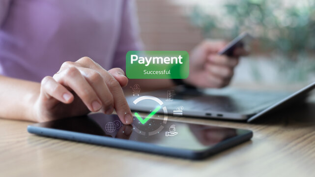 Hand touching tablet with payment successful message and financial icons, representing digital transaction, mobile payment, and online wallet system.