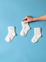 Hand is holding cotton white socks flat lay. Clothing production, sewing workshop