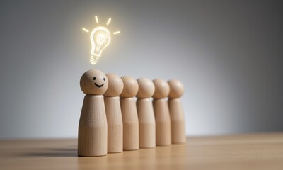 Wooden figures in a row with one figure smiling and a glowing lightbulb above its head